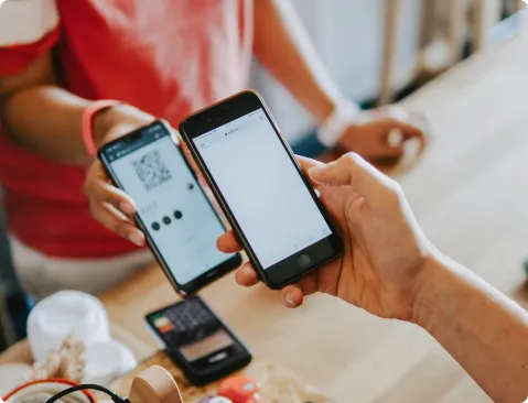 Una persona utiliza un smartphone para escanear un código QR en otro teléfono, simbolizando una moderna taquilla digital.
